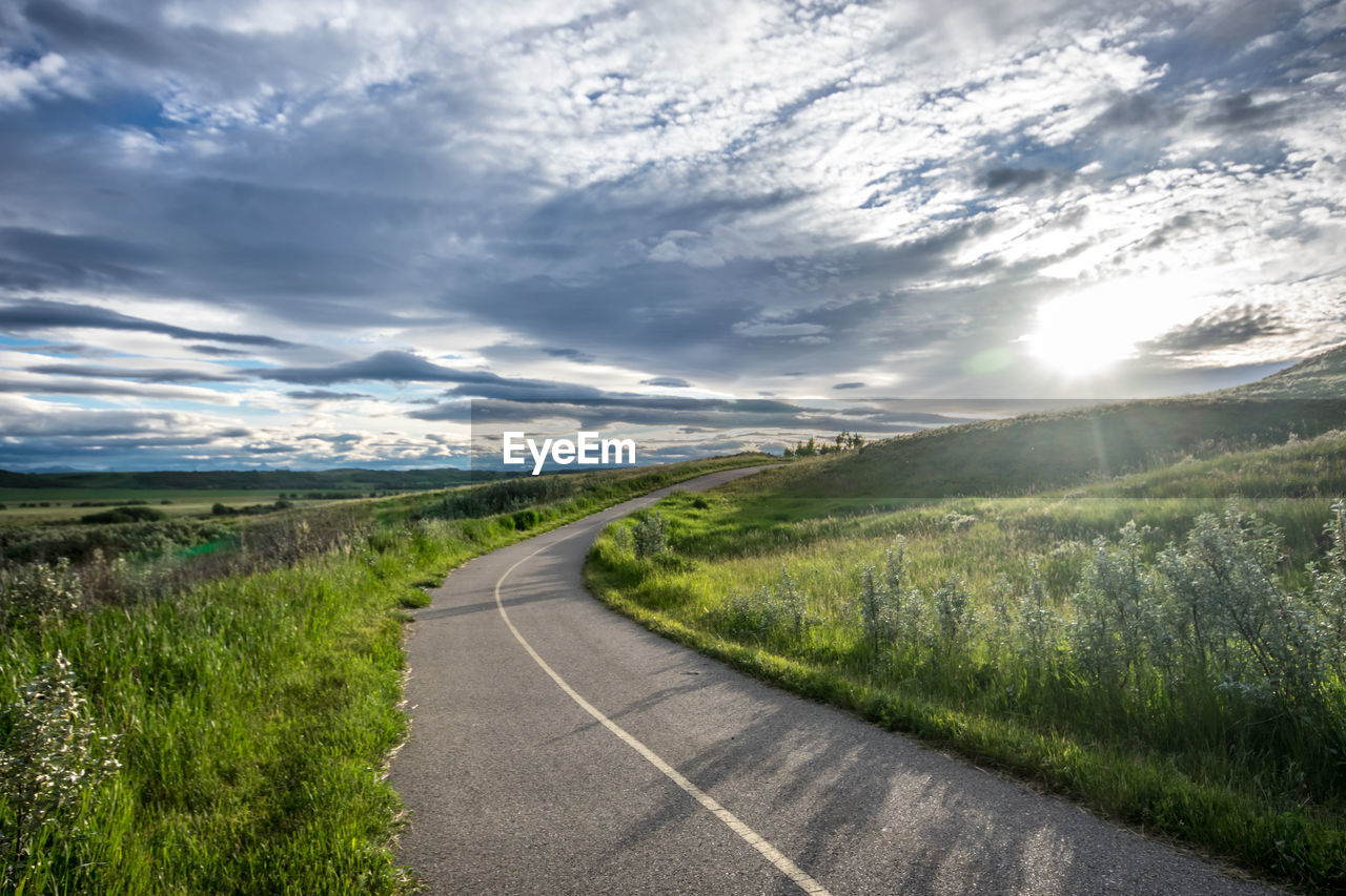 Road amidst field against sky