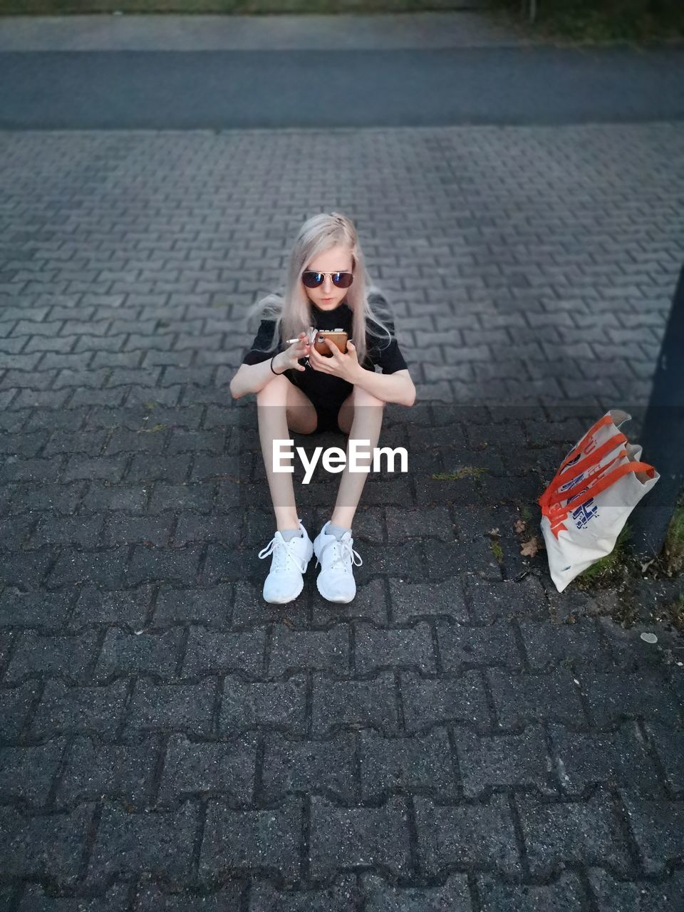 PORTRAIT OF A WOMAN SITTING ON FOOTPATH