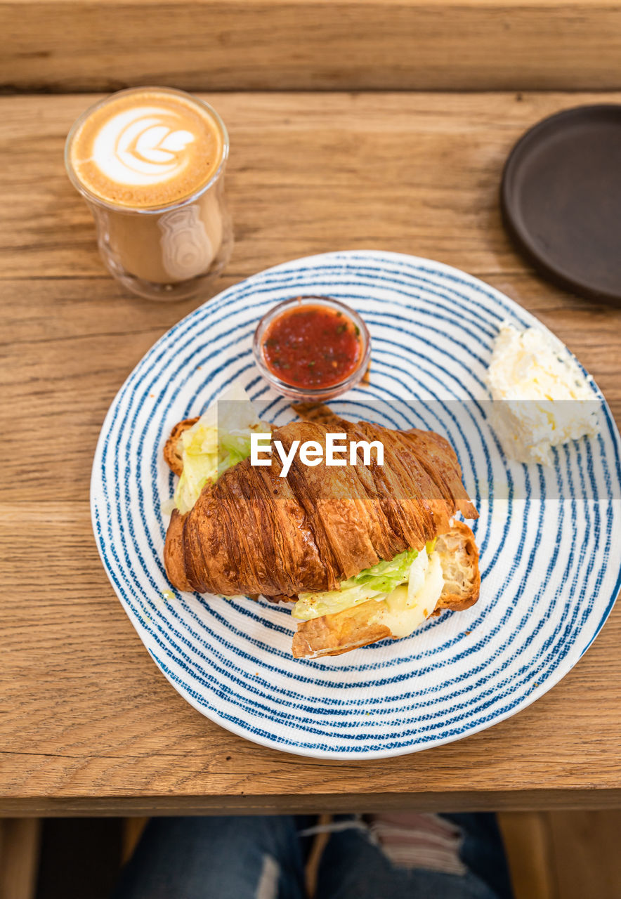 Croissant with grilled cheese and salad  and cup of cappuccino with latte art.  breakfast or lunch.