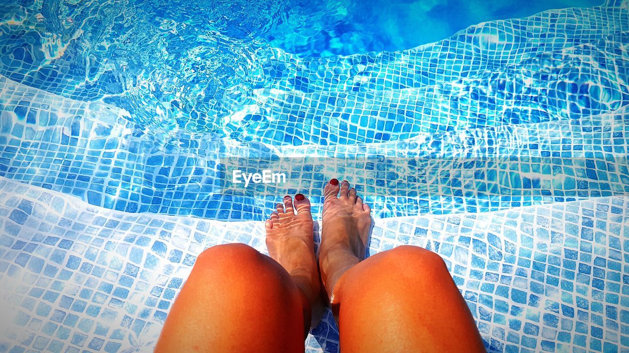 Low section of woman sitting in swimming pool