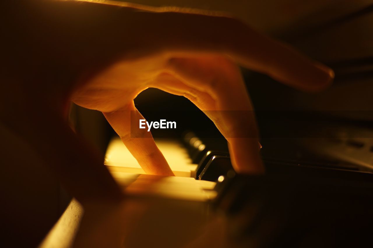 Close-up of human hand playing piano