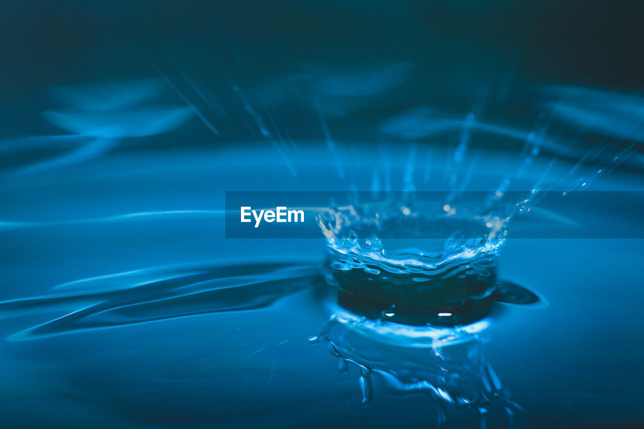 CLOSE-UP OF WATER SPLASHING AGAINST BLUE BACKGROUND