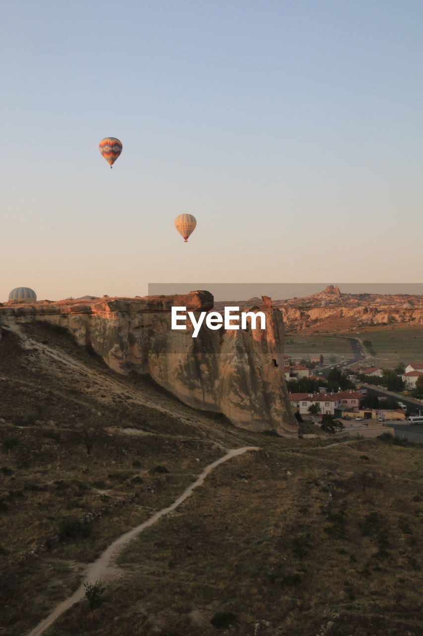 Hot air balloons flying over land against sky during sunset