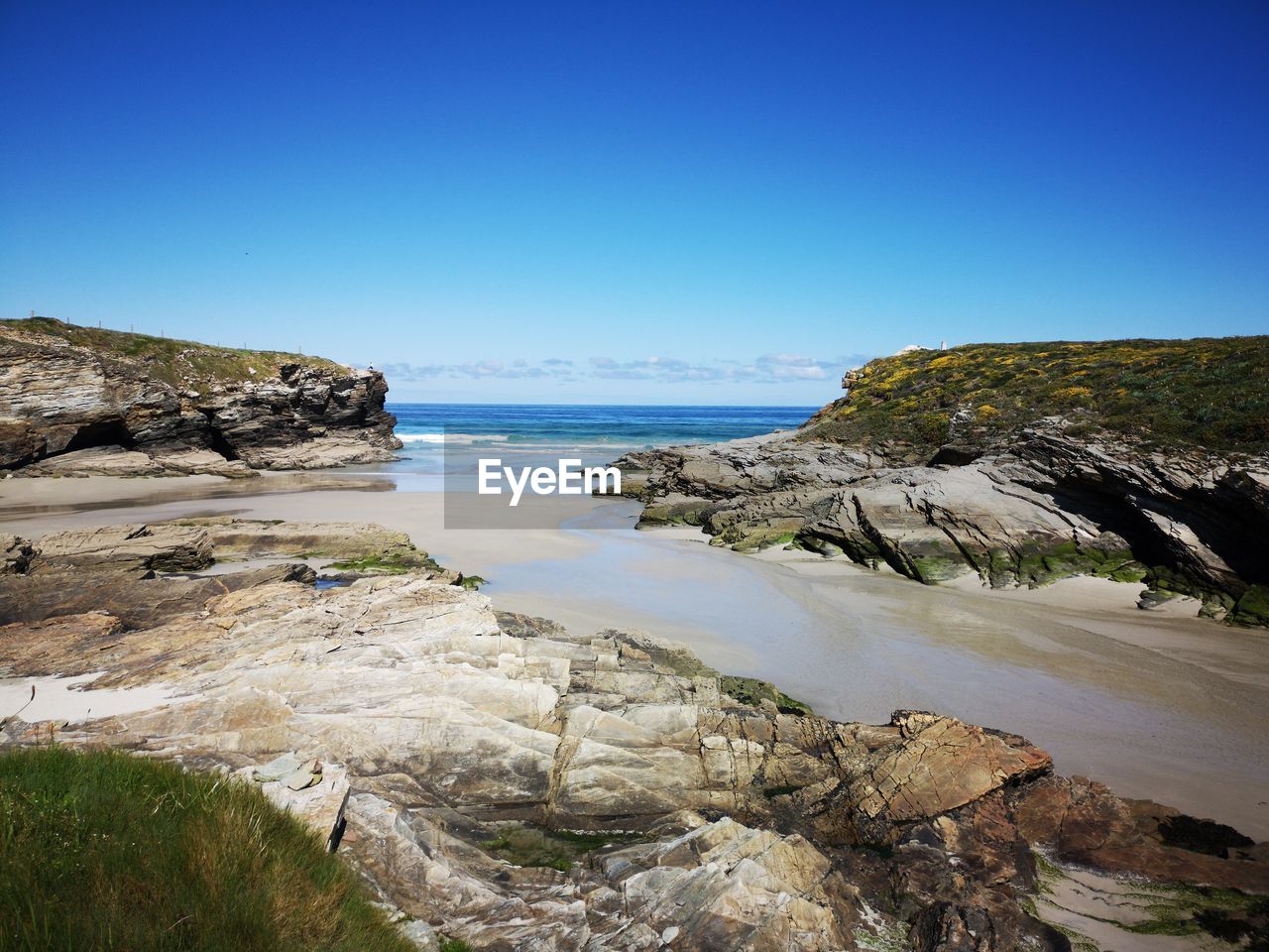 Scenic view of beach against clear blue sky