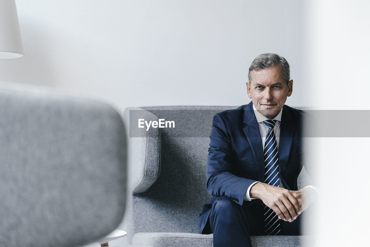 Portrait of mature businessman sitting on couch in his office