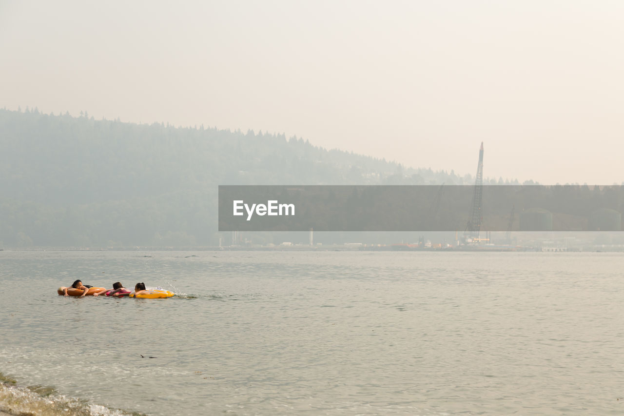 PEOPLE ON BOAT AGAINST RIVER