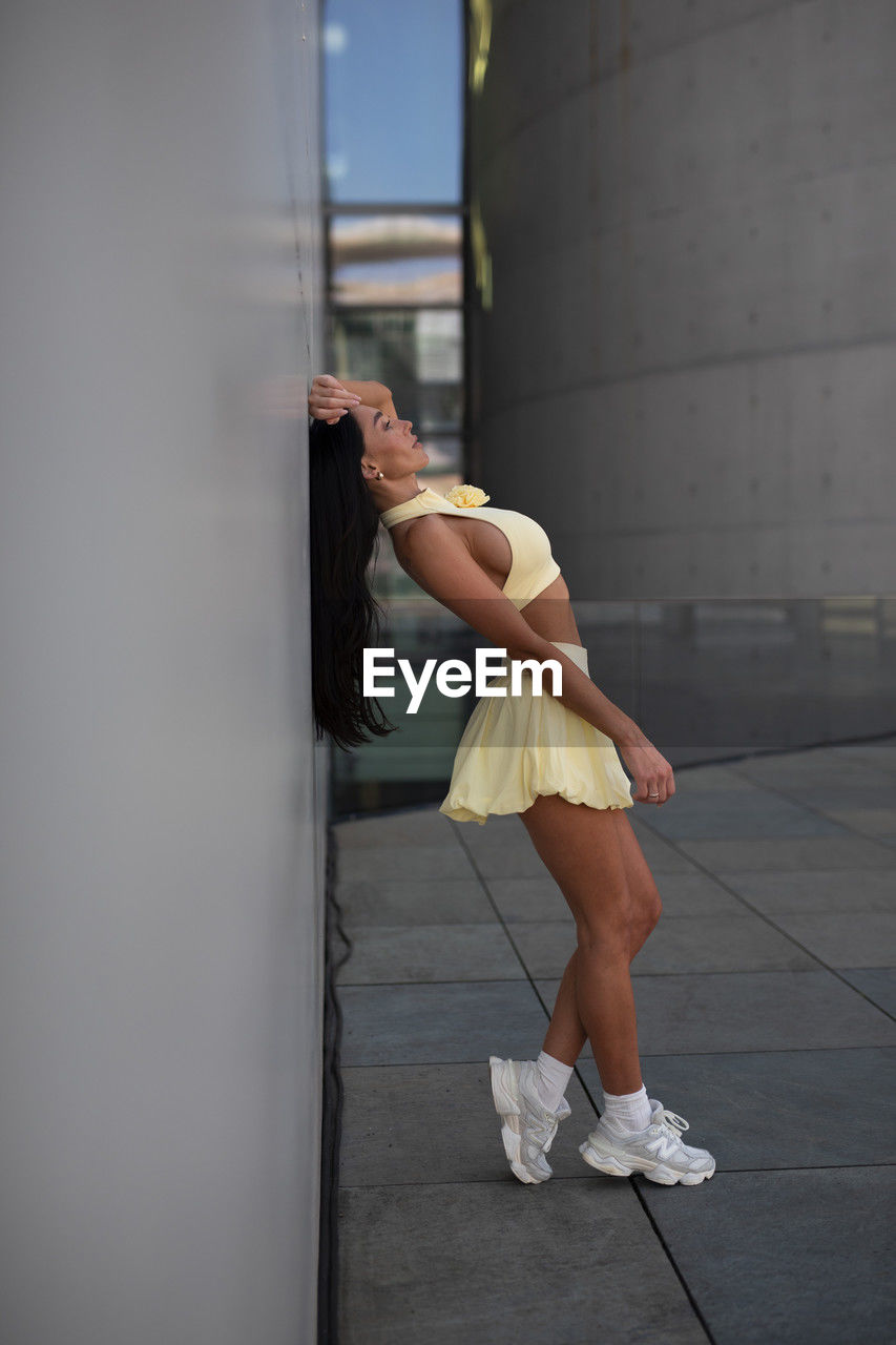 one person, adult, women, full length, young adult, exercising, lifestyles, clothing, architecture, white, sports, shoe, spring, fashion, side view, day, sports clothing, leisure activity, limb, city, hairstyle, vitality, casual clothing, standing, person, female, relaxation, copy space, athleticism, balance, outdoors, footwear, city life