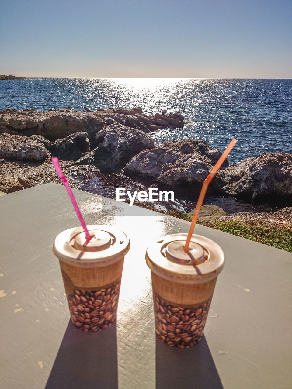 CLOSE-UP OF DRINK ON BEACH AGAINST SKY