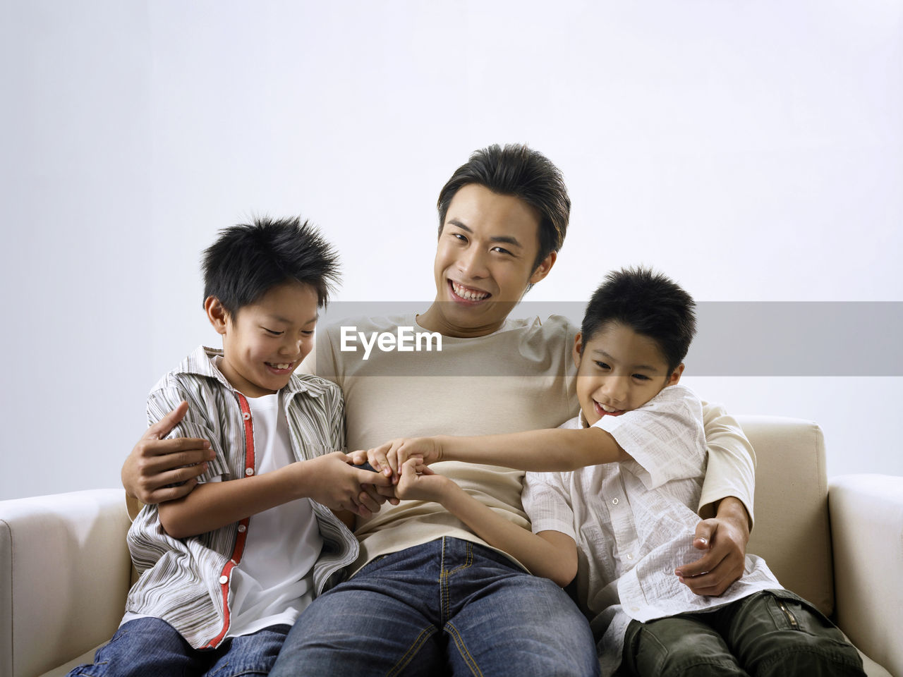 Portrait of smiling man with sons sitting on sofa