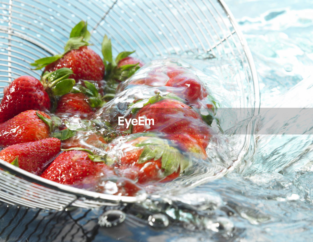 Close-up of strawberries being washed in colander