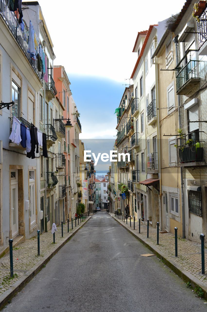 Empty road amidst buildings against sky