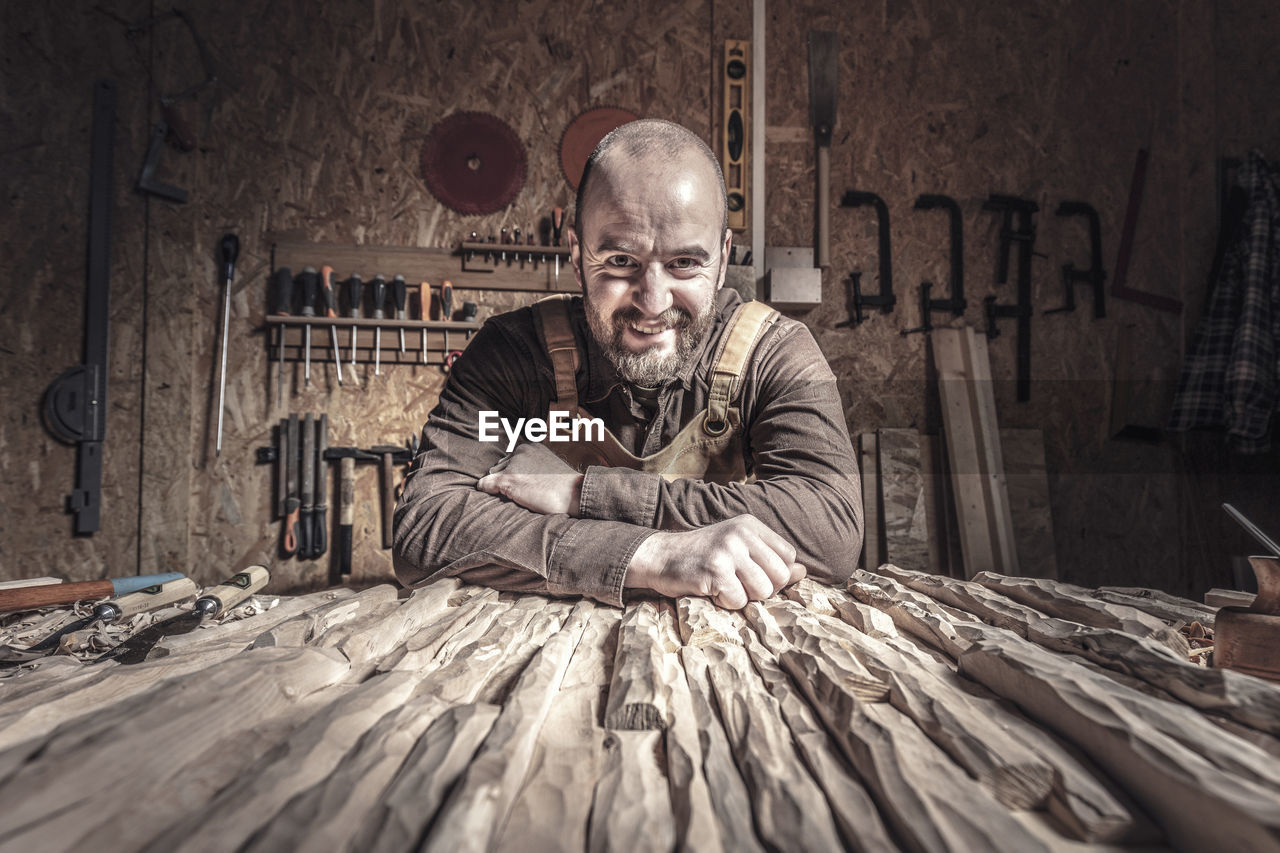 Portrait of smiling carver on table at workshop