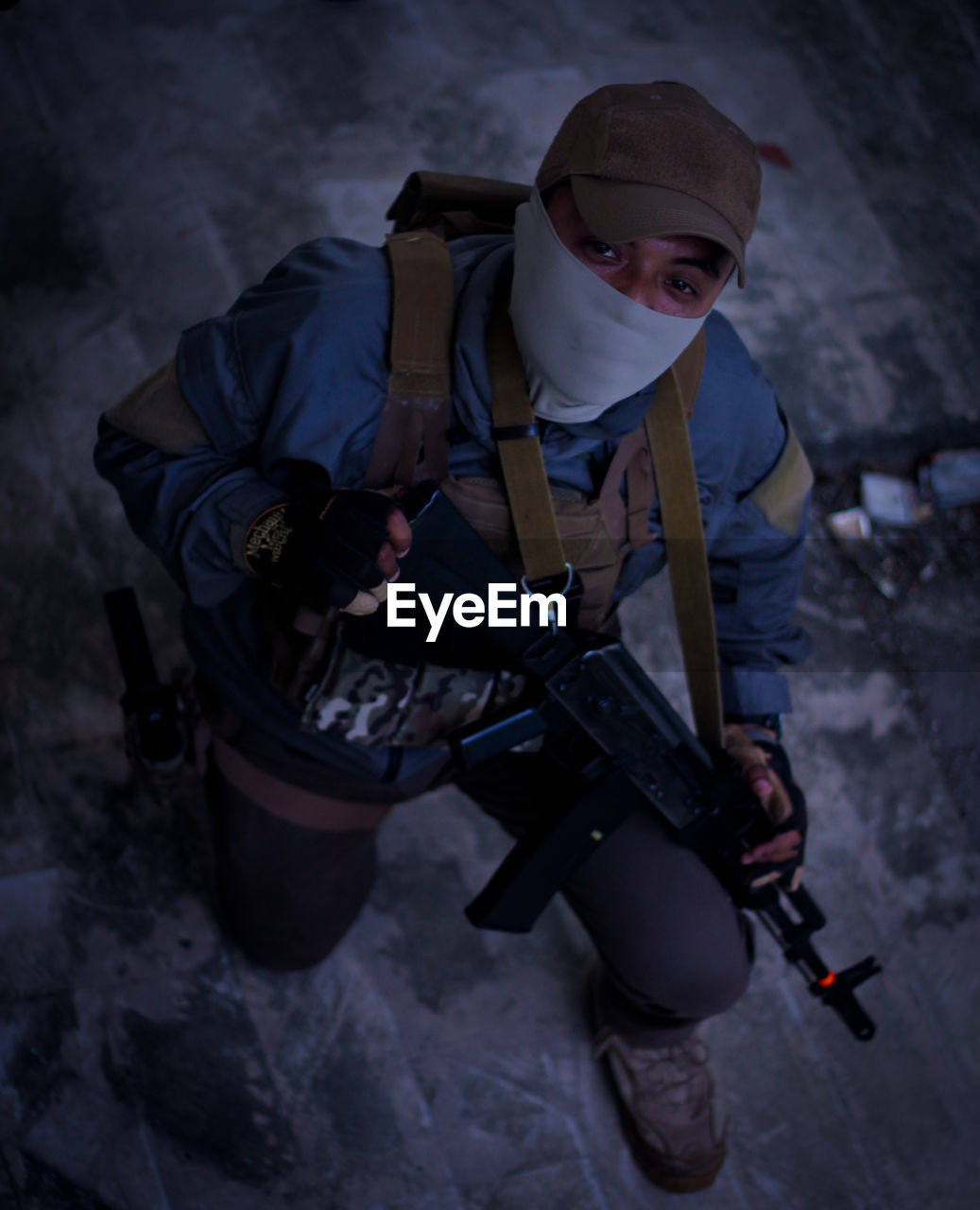 High angle portrait of young man holding rifle wearing mask standing outdoors