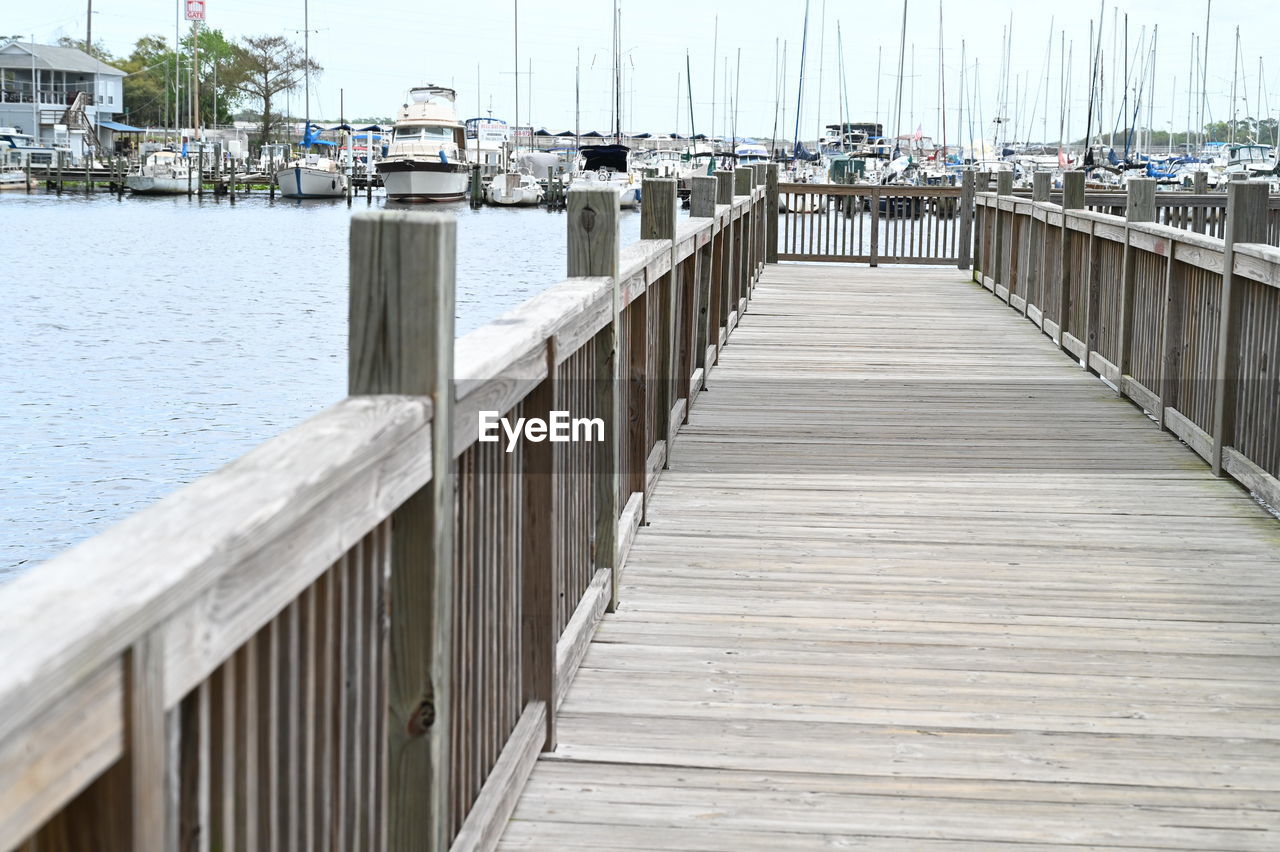 walkway, water, dock, boardwalk, pier, architecture, transportation, harbor, nautical vessel, wood, sea, nature, day, no people, sky, marina, built structure, mode of transportation, jetty, ship, outdoors, sailboat, railing, travel destinations, tranquility, beach, travel, moored, the way forward, city, bridge, footpath, waterway, tourism, beauty in nature, land