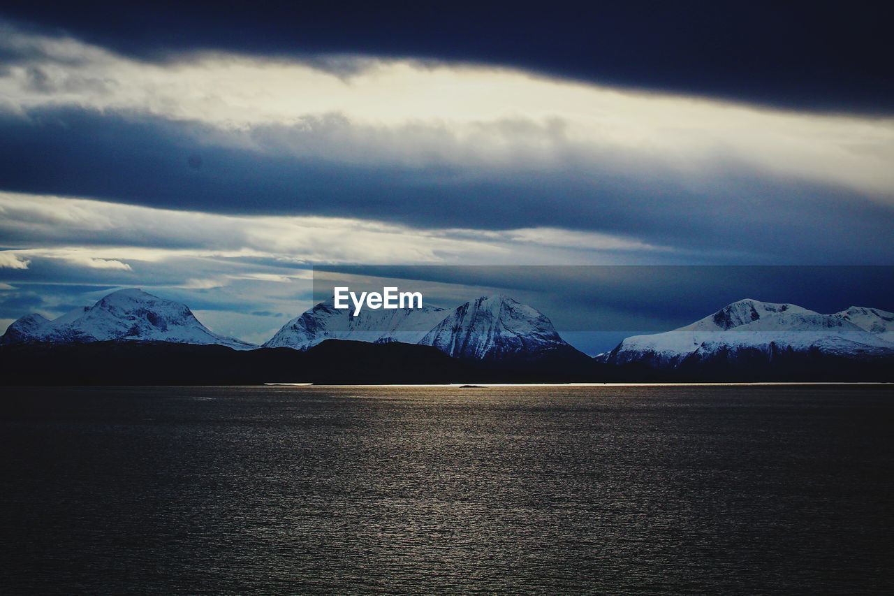 SCENIC VIEW OF SNOWCAPPED MOUNTAINS BY LAKE AGAINST SKY