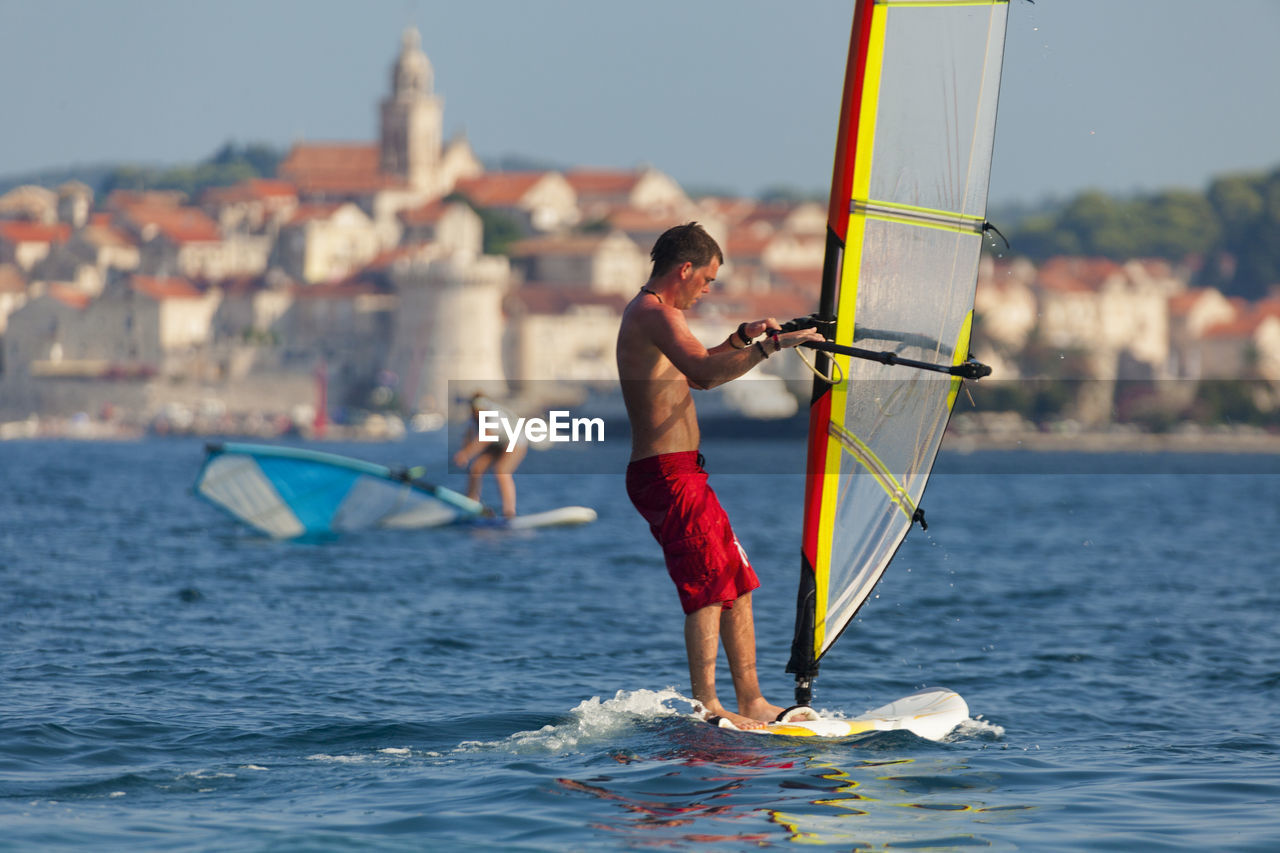 FULL LENGTH OF SHIRTLESS MAN HOLDING SEA