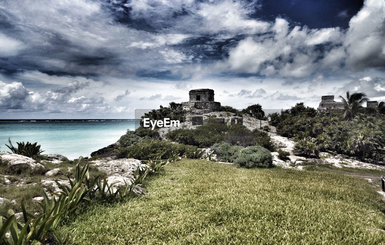 VIEW OF CASTLE ON COAST AGAINST CLOUDY SKY