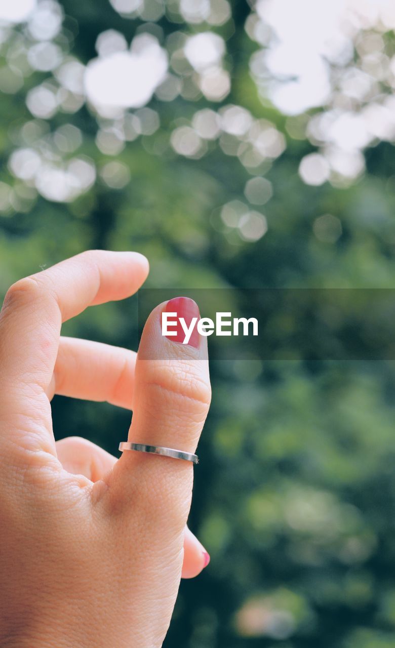 Cropped hand wearing ring against plants