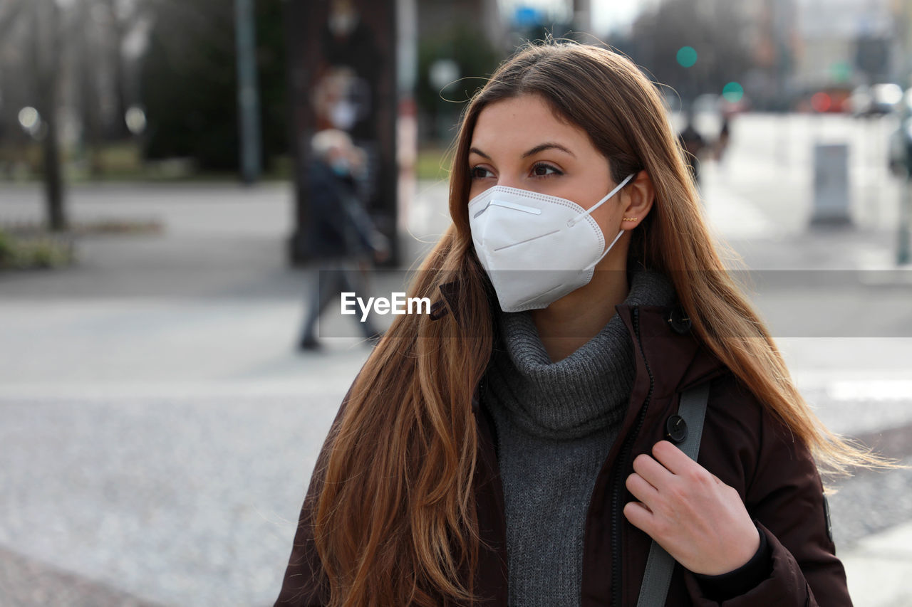 Young woman wearing mask while looking away in city