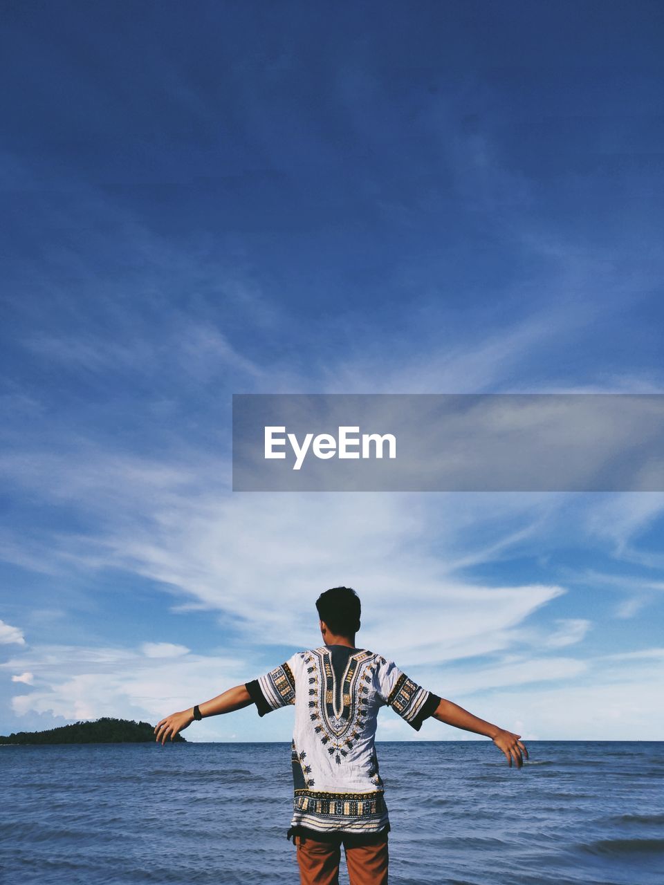 Rear view of man standing against sea at beach