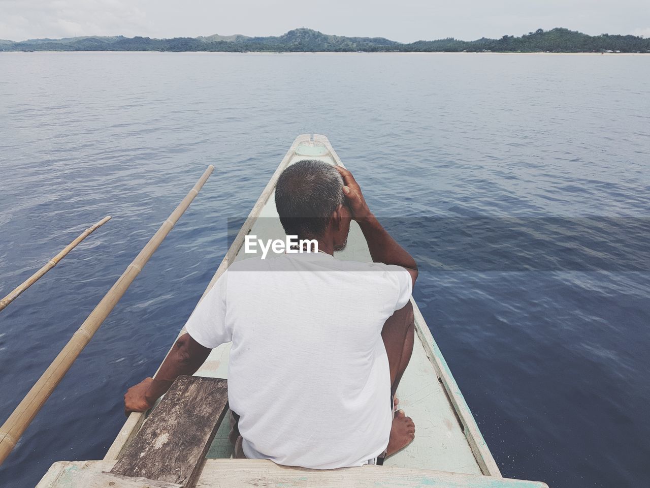 Rear view of man sitting on boat in sea