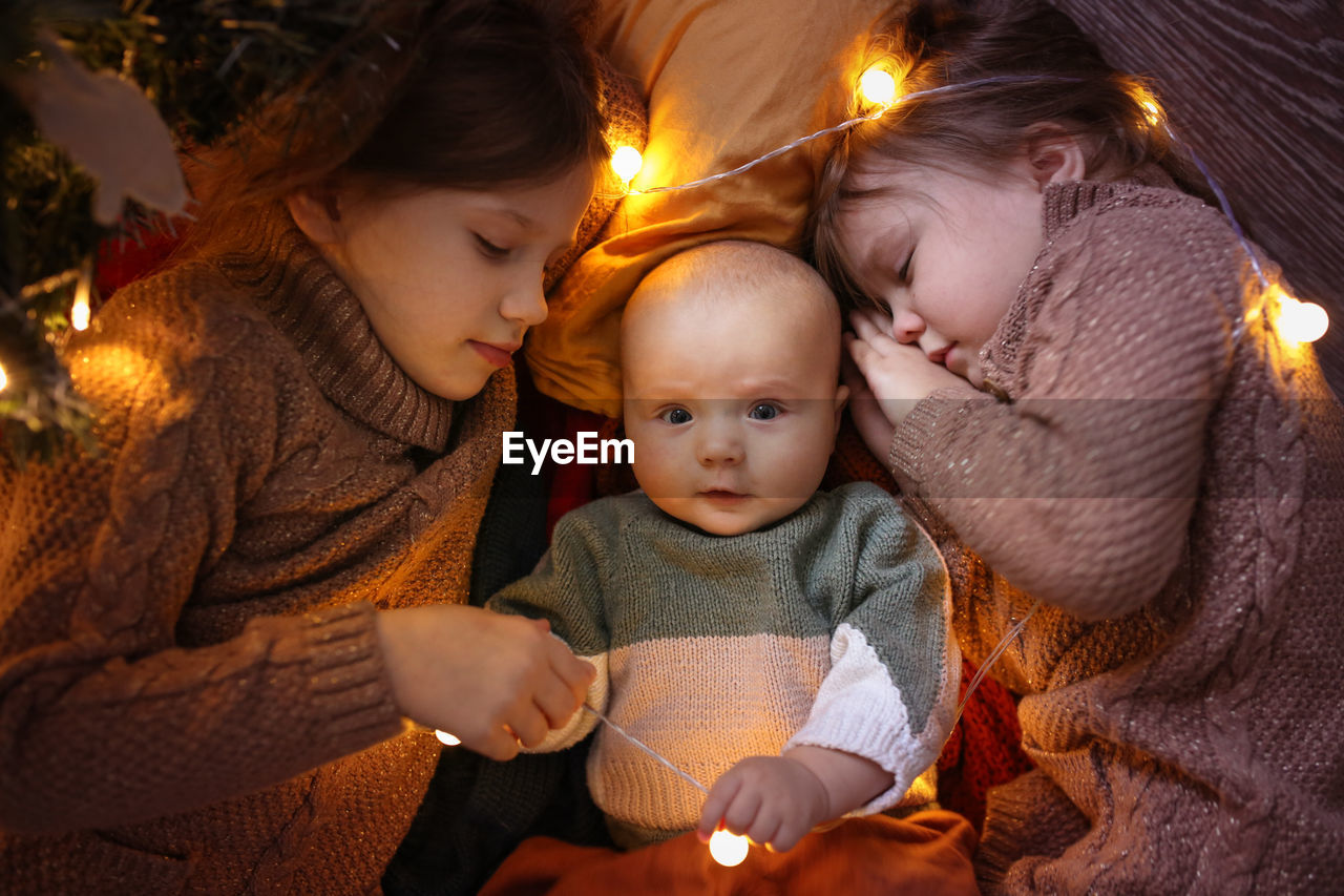 Funny children sleep together and embrace in a dark cozy interior, in warm sweaters 