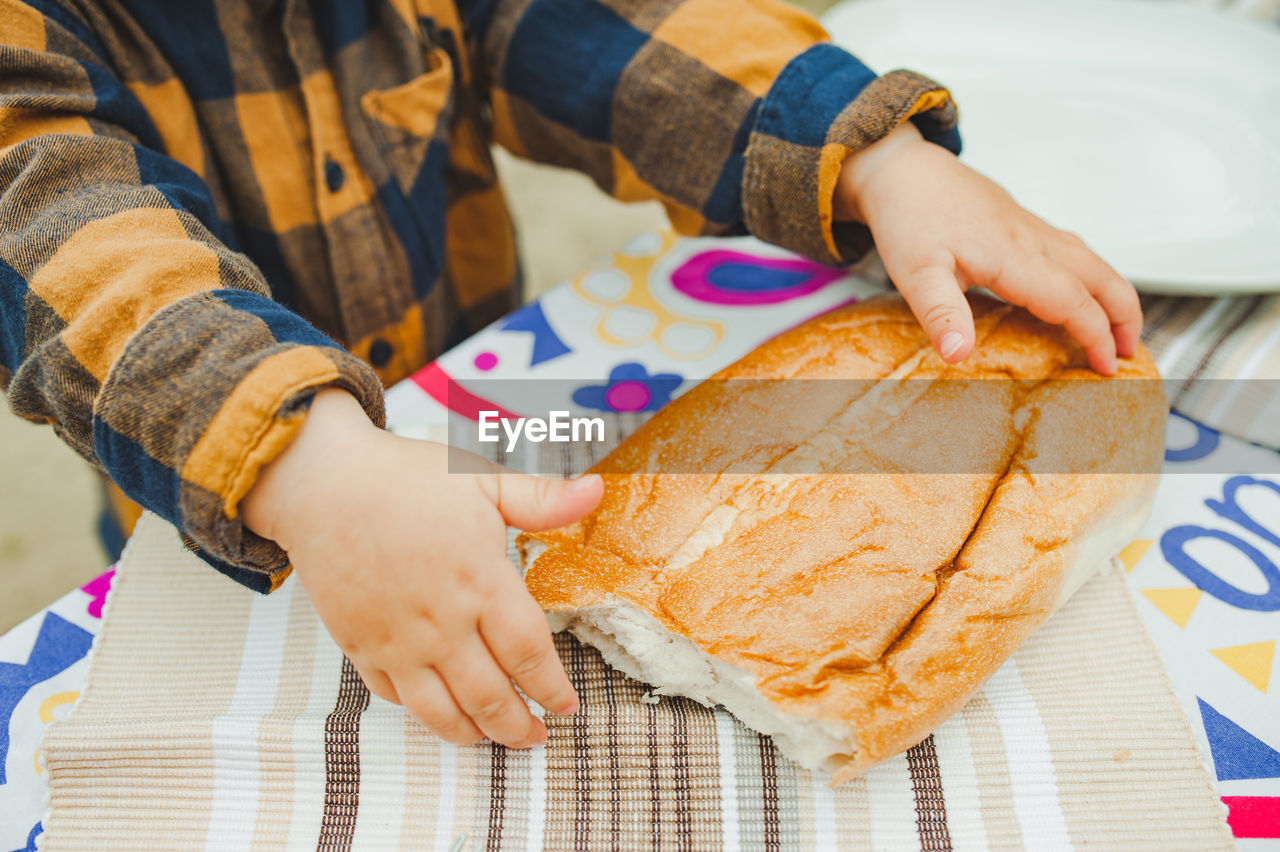 Small hand child in checkered rustic child is holding fresh homemade bread. selective focus