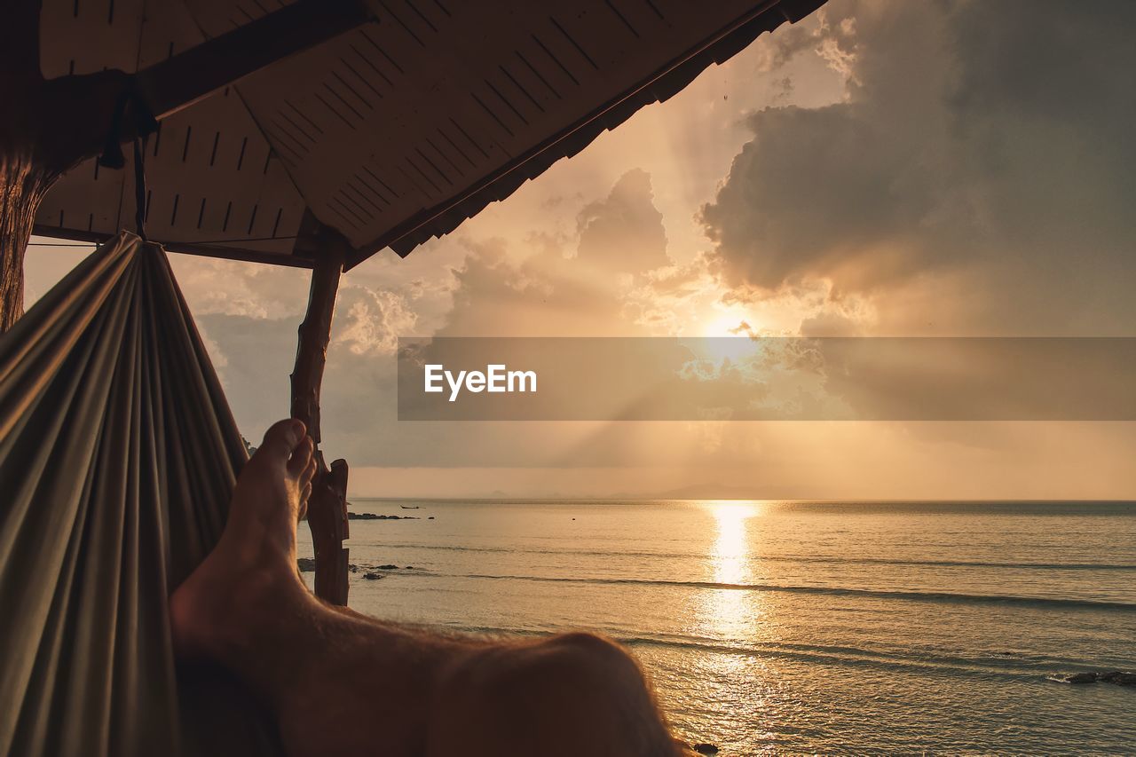 Man relaxing against sea during sunset