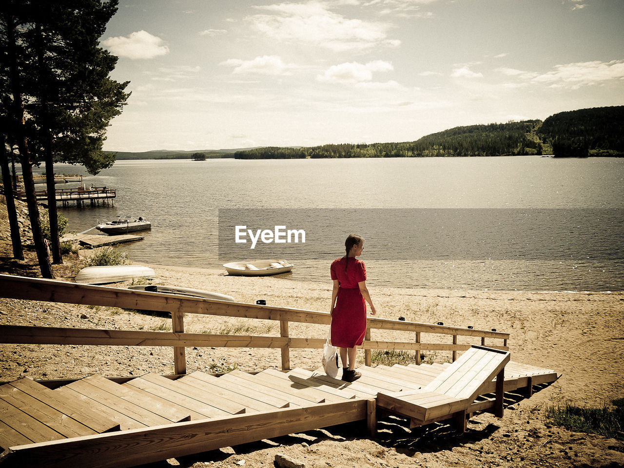 Rear view of woman standing on pier against lake