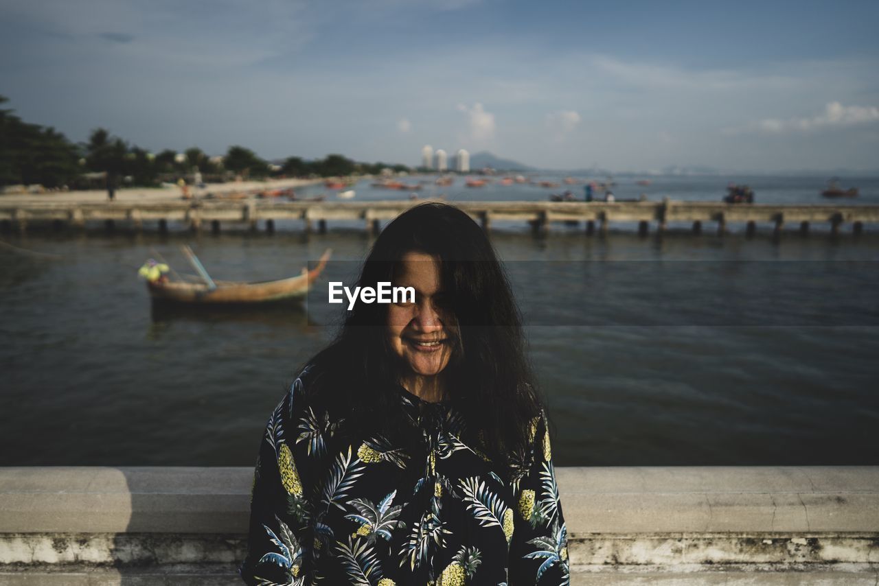 Portrait of smiling woman standing against sea