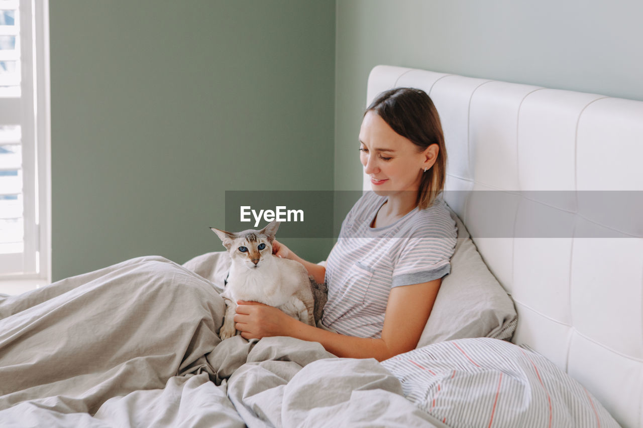 Young woman sitting on bed at home