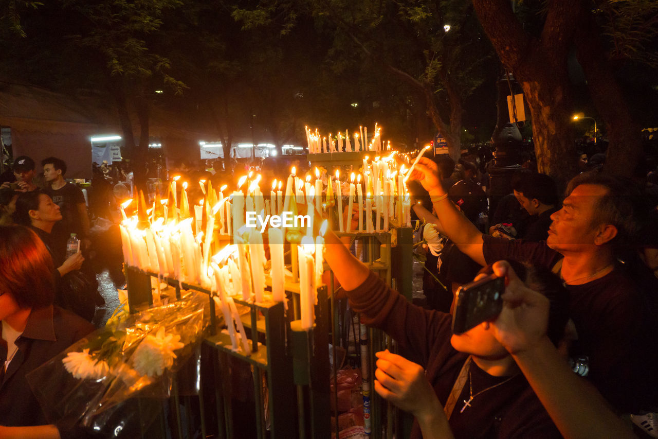 CLOSE-UP OF PEOPLE ON ILLUMINATED STREET LIGHT