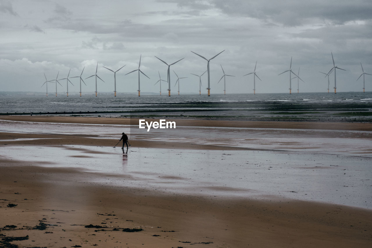 Scenic view of beach with person on sand against sky