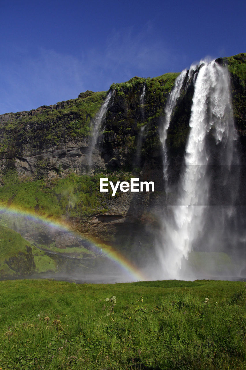 SCENIC VIEW OF WATERFALL AGAINST RAINBOW IN SKY