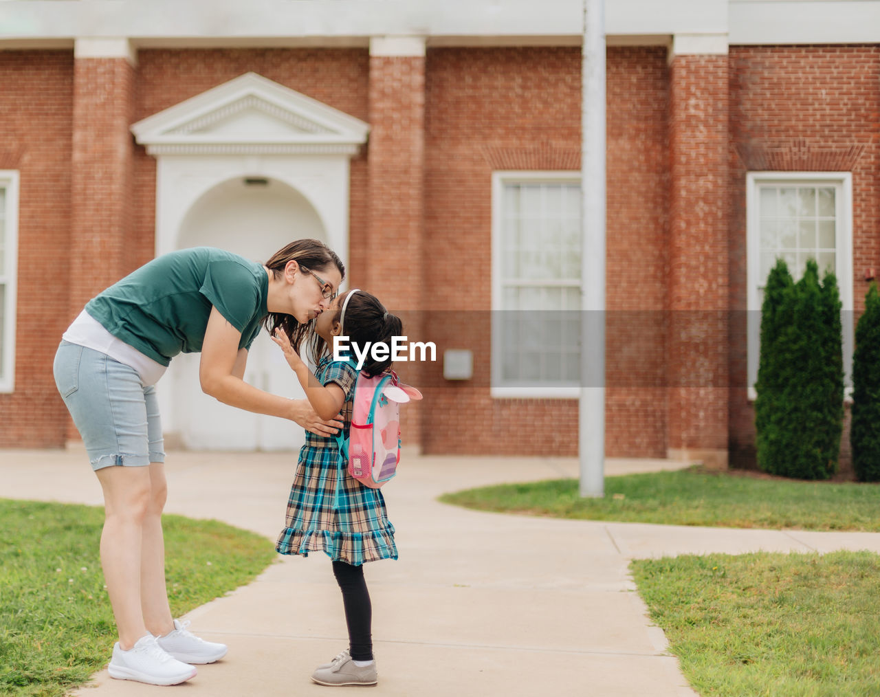 Young millennial mother sending daughter off back to school