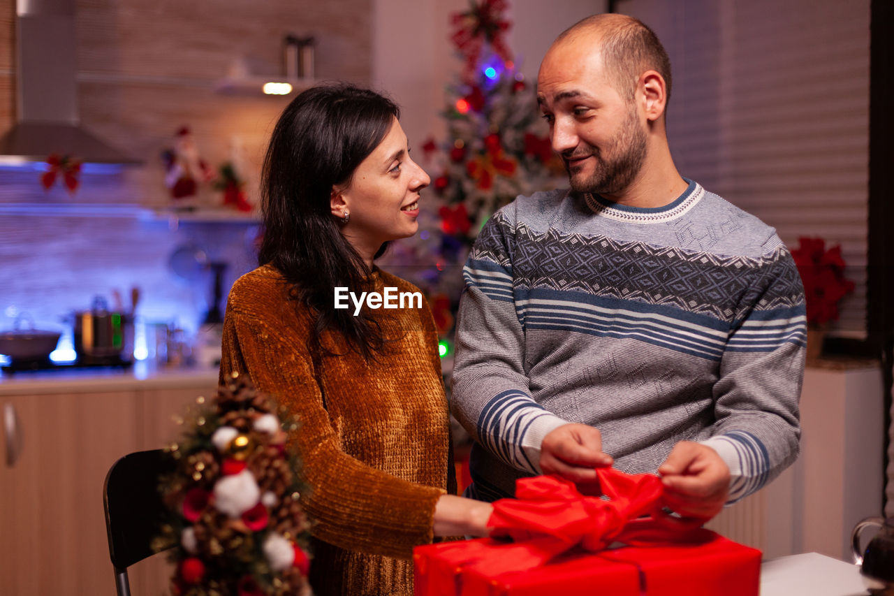 Smiling couple holding gift at home