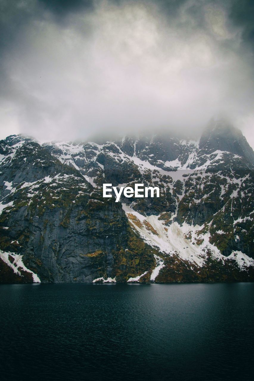 Scenic view of lake by snowcapped mountains against sky