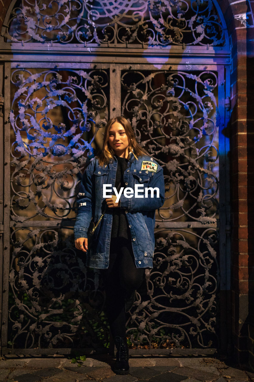 Fashionable young woman in city at night