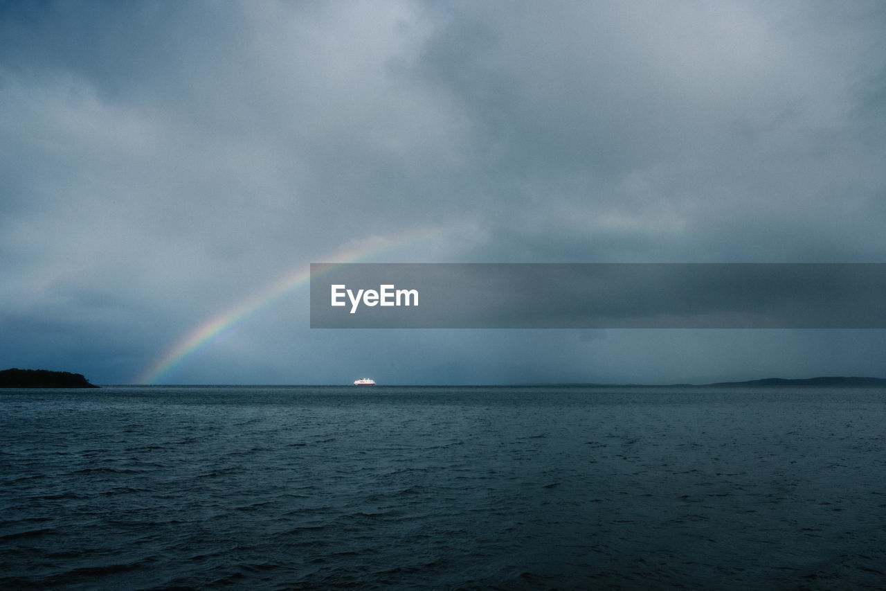 Scenic view of rainbow over a ship and sea against sky