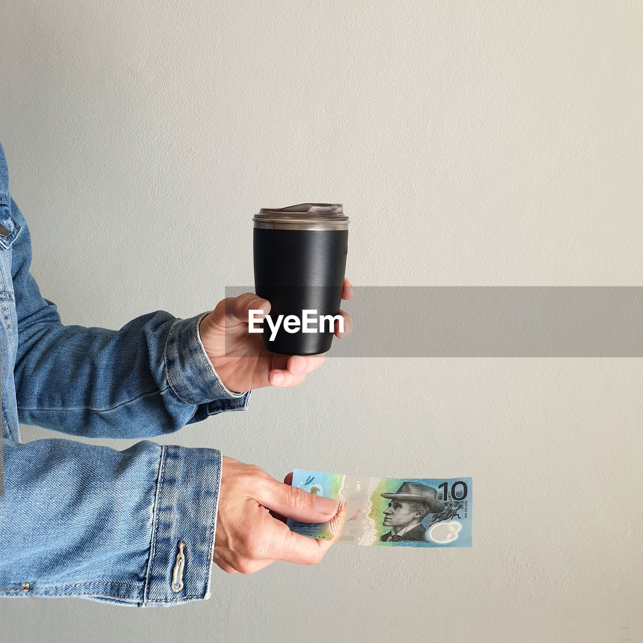 Person paying for coffee with australian money holding reusable coffee cup