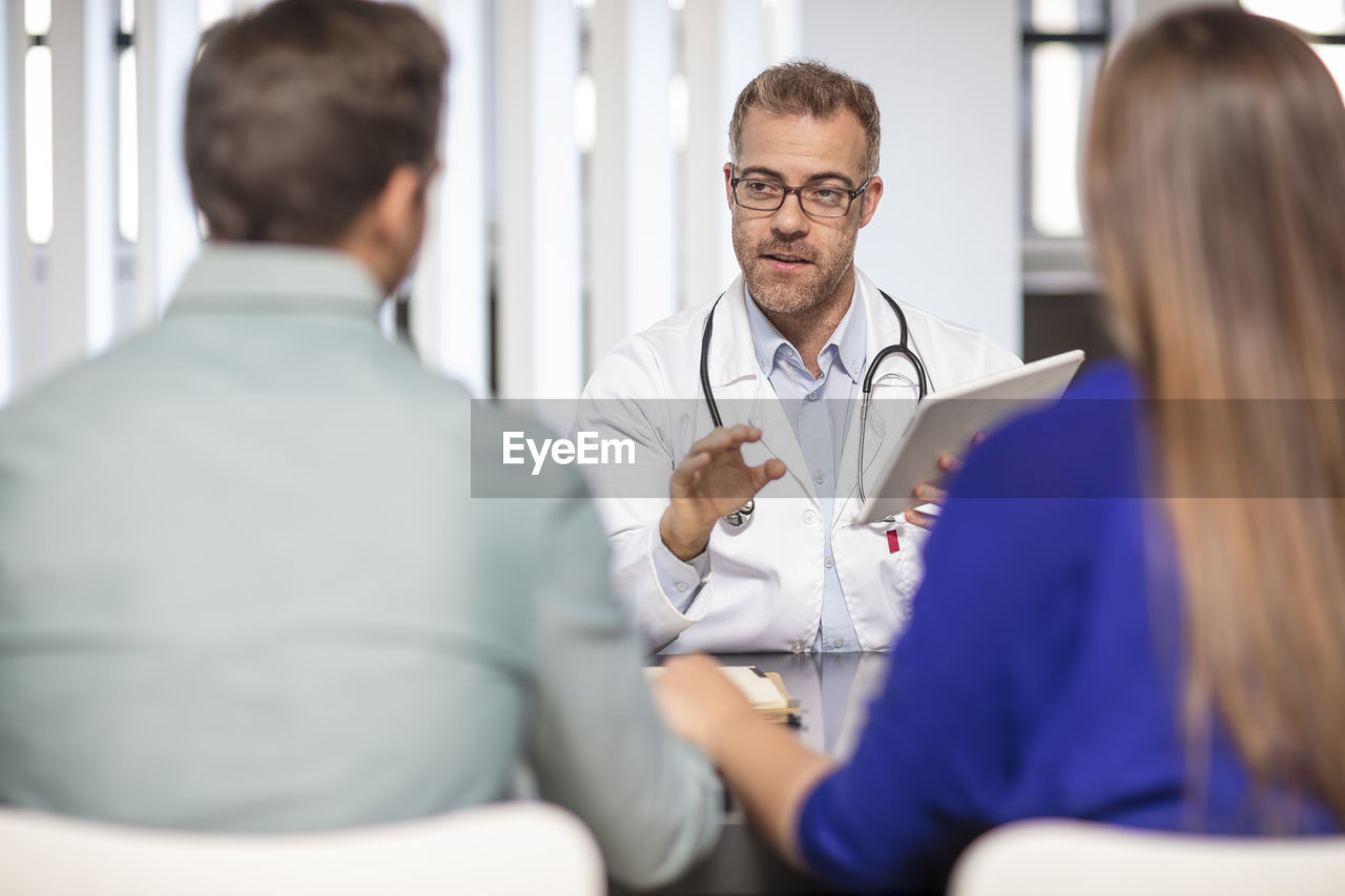 Doctor talking to couple in medical practice