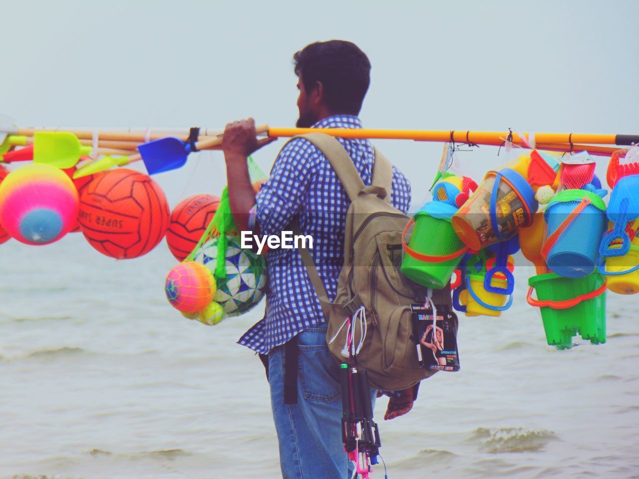 MAN HOLDING MULTI COLORED UMBRELLAS ON BEACH