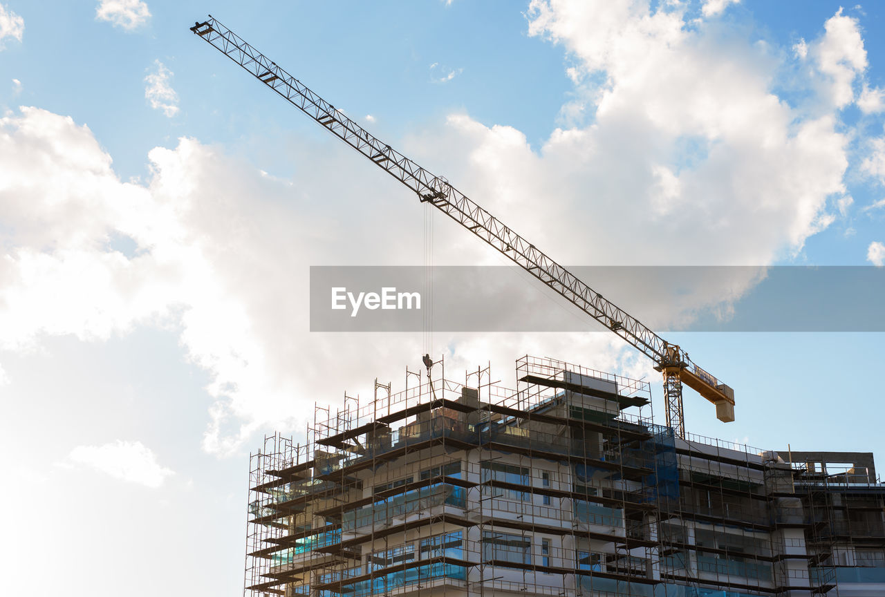 LOW ANGLE VIEW OF CRANES AGAINST BUILDING