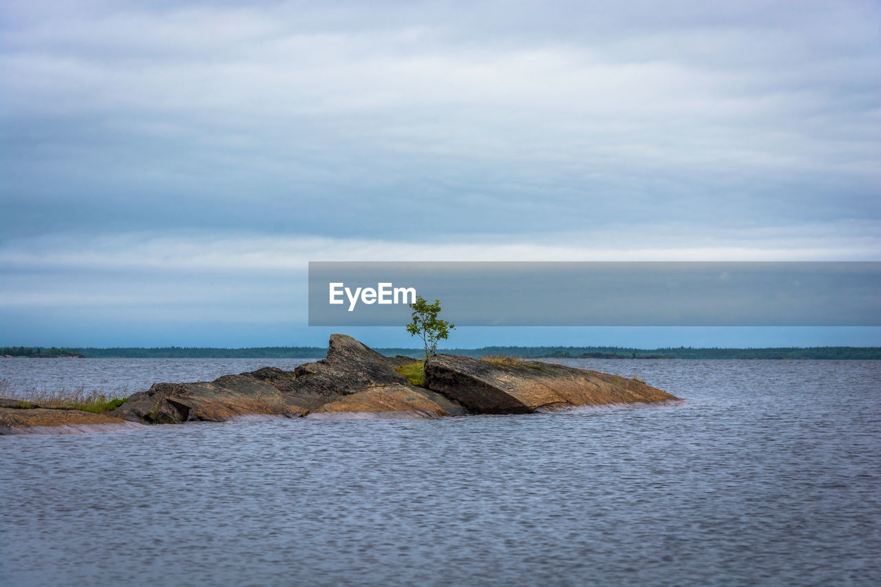 Scenic view of rocks by sea against sky