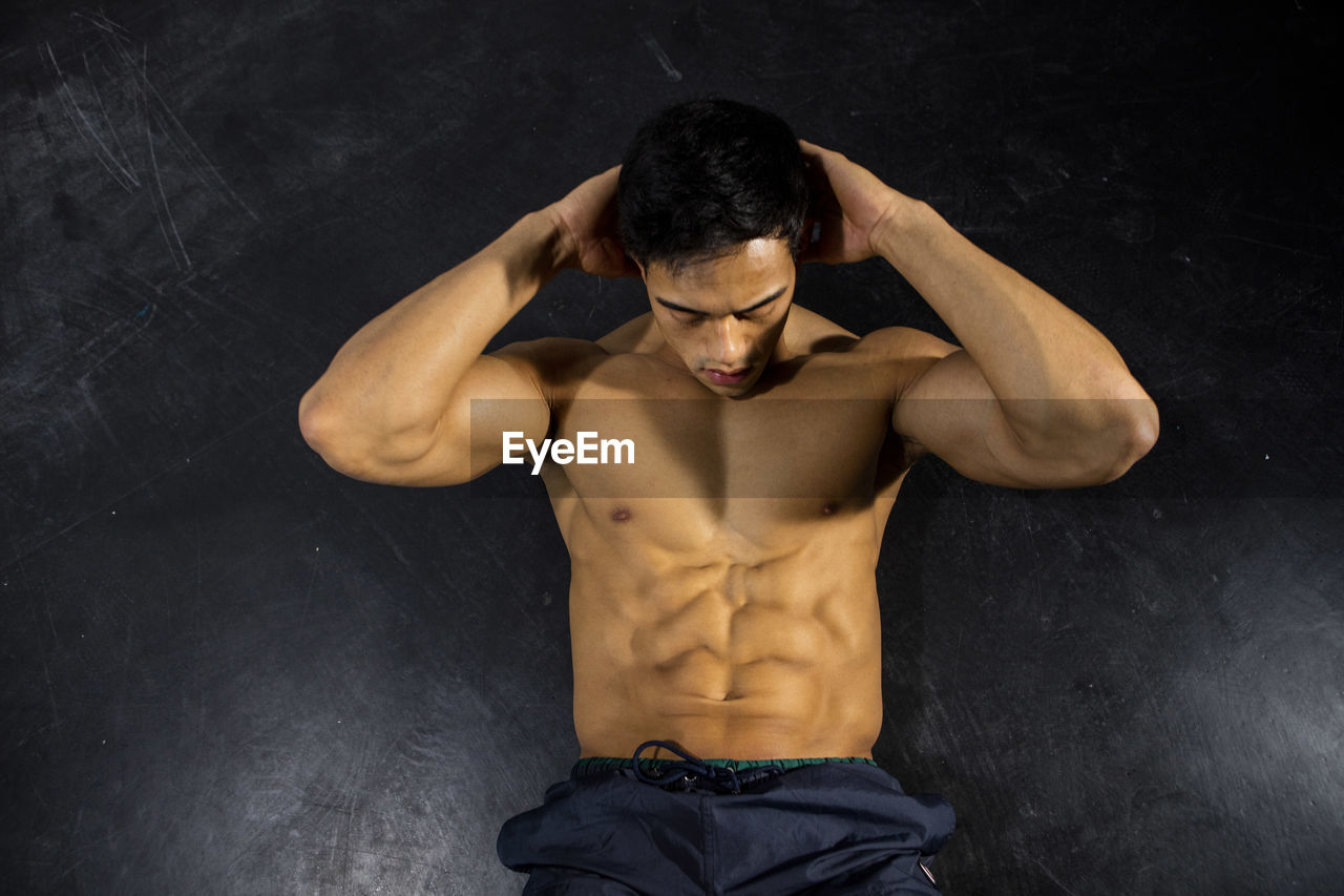Shirtless muscular man exercising against wall