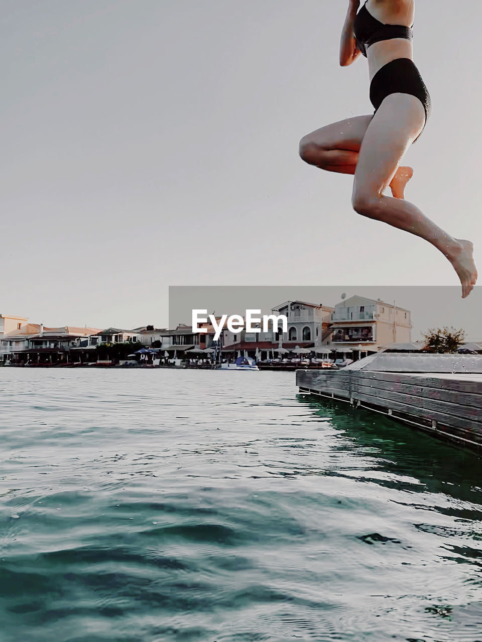 Girl jumping over sea against clear sky