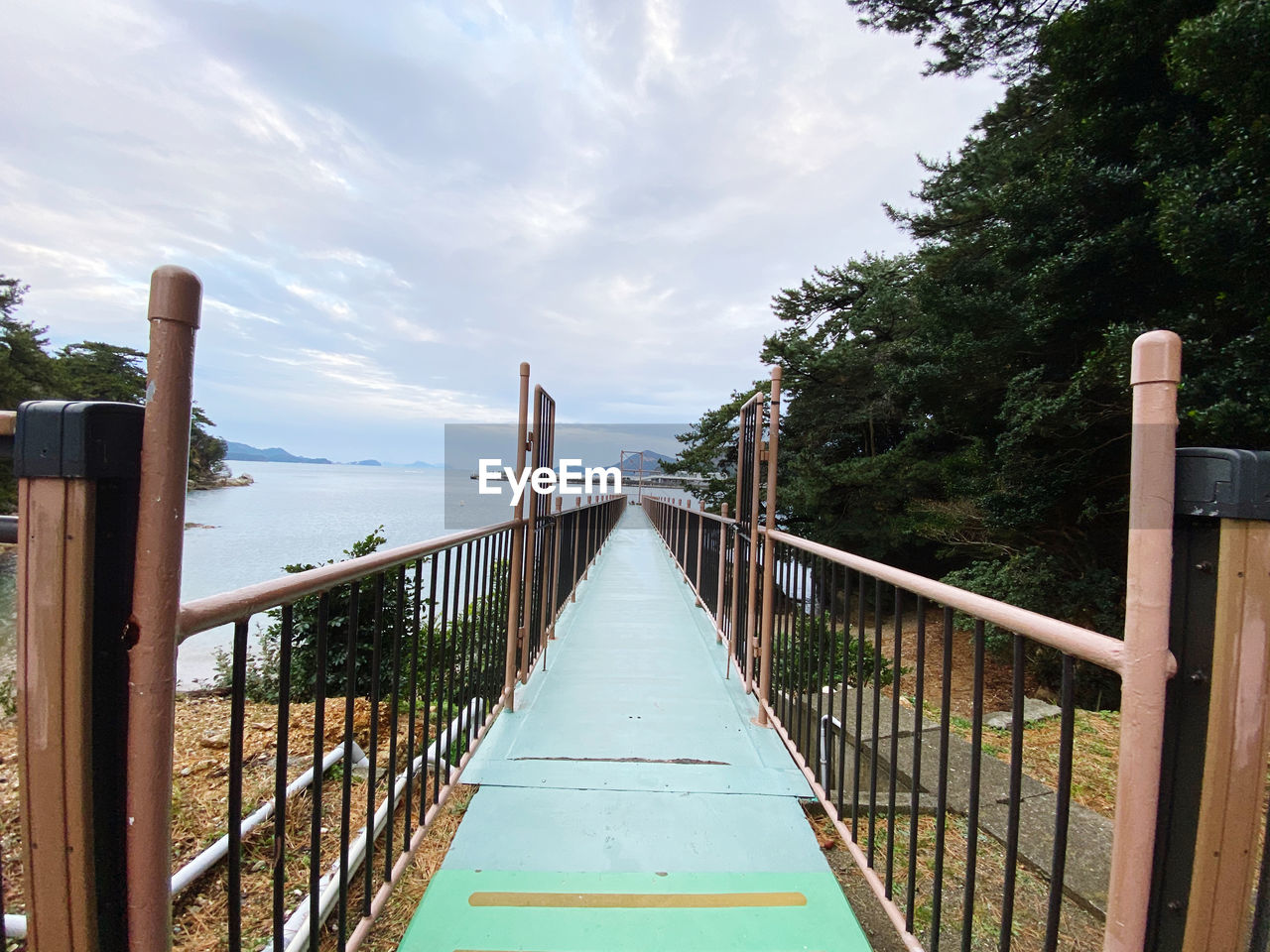 Footbridge over sea against sky