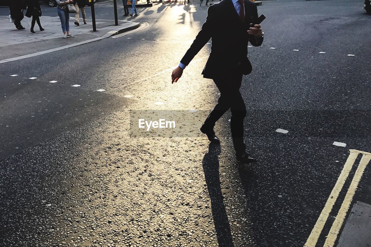 Low section of businessman walking on road