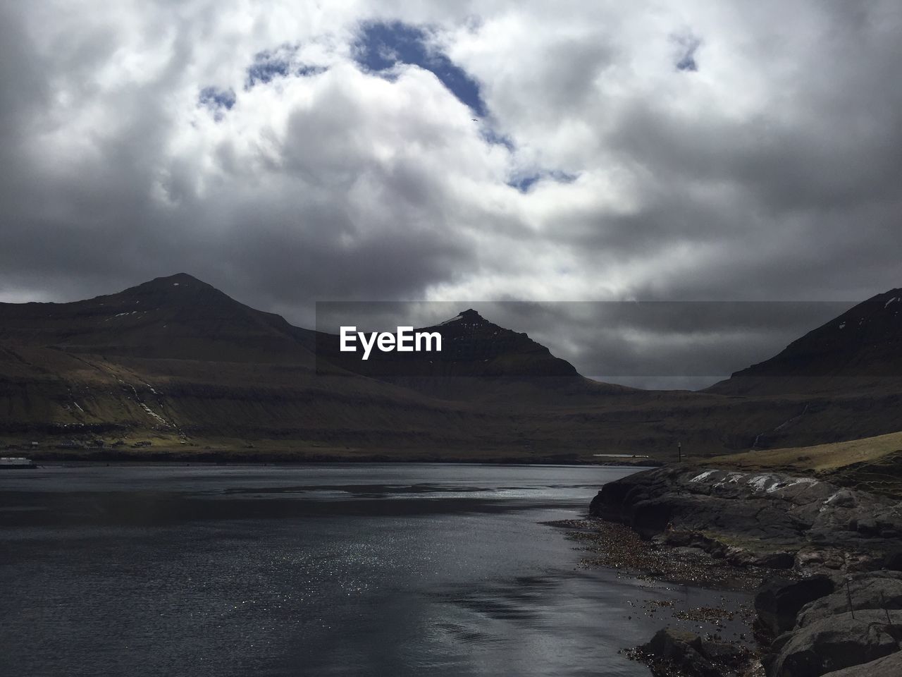 VIEW OF CALM SEA AGAINST MOUNTAIN RANGE