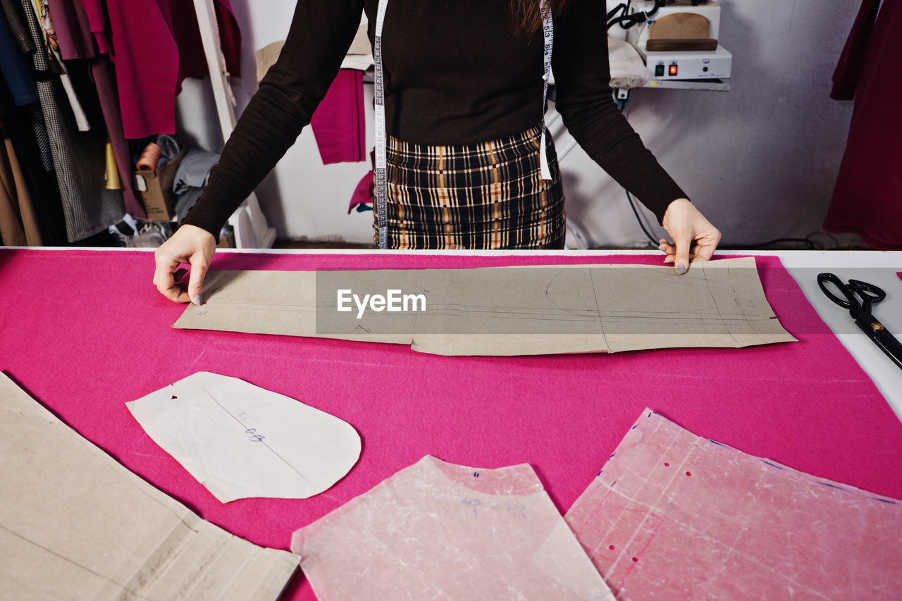 Seamstress working with sewing pattern on table in tailor shop